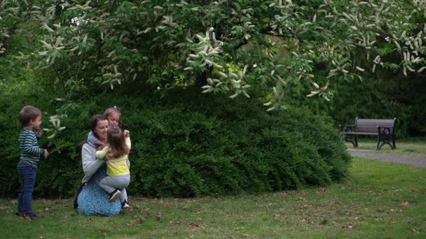 Щаслива родина мама Три маленьких брати і сестри діти весело дме бульбашки насолоджуючись літнім відпочинком в садовому парку. Усміхнені батьки діти проводять дозвілля разом увечері на заході сонця Мати Мати — стокове відео