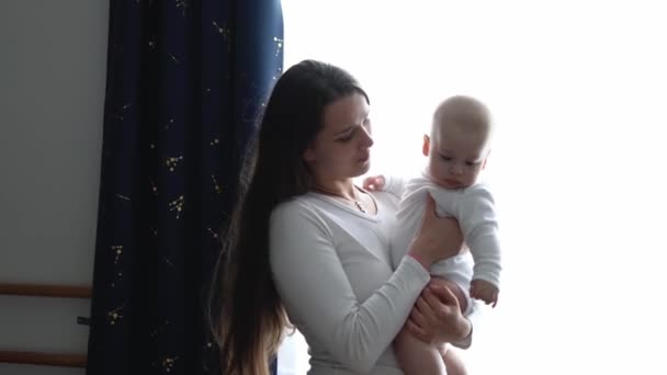 Loving Tender Caucasian Young Mum Holding Adorable Cute Baby Boy Son Embracing Kissing Small Kid. Happy Affectionate Long Haired Mother Cuddling With Infant Child Girl Daughter Care Standing At Home. — ストック動画