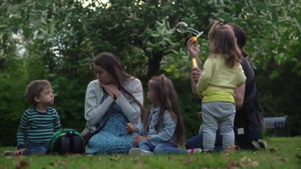 Glückliche Familienmutter Vater Drei kleine Geschwister Kinder haben Spaß beim Blasenblasen und genießen die Sommerferien im Gartenpark. Lächeln Eltern Kinder verbringen Freizeit zusammen Abend Sonnenuntergang — Stockvideo