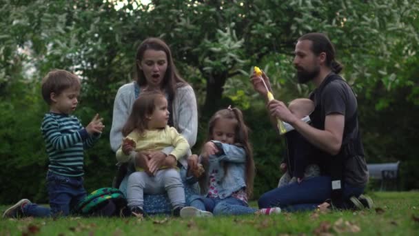 Happy family mother Father Three four Baby little siblings kids have fun blowing bubbles enjoying summer holidays in garden park. Smiling parents children spending leisure time together evening sunset — Video Stock