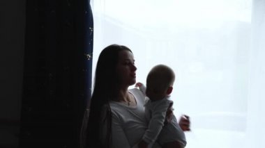 Siluet Sevecen, Şefkatli Kafkas Genç Anne Sevimli Bebek Oğlu Kucağında Küçük Çocuğu Kucaklıyor. Mutlu Uzun Saçlı Anne Evde Bebek Kızına Kucaklıyor.