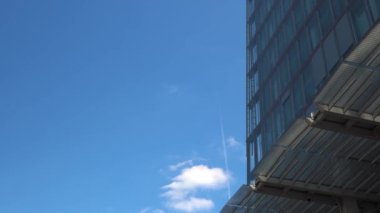 Londra 'daki gökdelenlerin iş merkezinin üzerinden geçen uçak. Öğleden sonra bulutlu, mavi gökyüzünde uçan bir uçakla yüksek binaların alt görüntüsü. Hava Taşımacılığı, Seyahat, Meslek kavramı