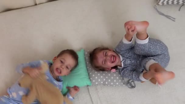 Two Smiling Prechool Toddler Children Pajamas Playing Teddy Bear Bed — стоковое видео