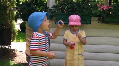 Güzel anaokulu şakaları. Çocuklar ve kızlar sıcak yaz aylarında sabun köpüğü üflüyor. Çocuklar bahçede oynuyorlar. Parkta bebek ya da açık havada güneşli bir günde bahçe. Çocukluk, Meslek, Ebeveynlik, Aile kavramı.