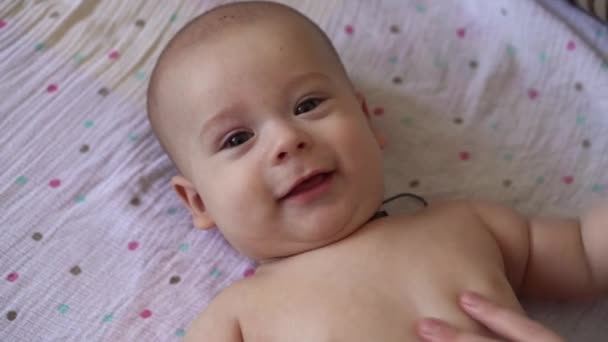 小さな裸のオムツ新生児の赤ちゃんは面白い笑顔 後ろに横たわっている 幸せな遊び心のある精力的な子供の肖像足の指をかむマッサージ医学小児科は 単純な運動骨の筋肉を強く行う — ストック動画