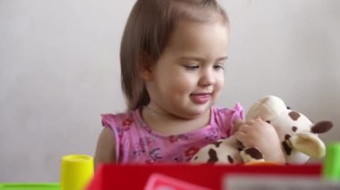 Küçük kız evde oyuncak ayıyla oynarken komik ifadesiz suratını ekşitiyor. Çocukluk duyguları, üzüntü, mutluluk. yaramaz kaprisli çocuk. Çocuk pencereden dışarı bakıyor..