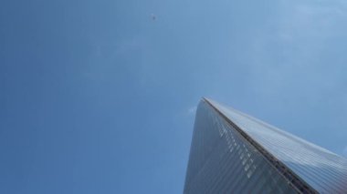 Londra 'daki gökdelenlerin iş merkezinin üzerinden geçen uçak. Öğleden sonra bulutlu, mavi gökyüzünde uçan bir uçakla yüksek binaların alt görüntüsü. Hava Taşımacılığı, Seyahat, Meslek kavramı