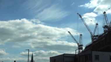 Londra 'daki gökdelenlerin iş merkezinin üzerinden geçen uçak. Öğleden sonra bulutlu, mavi gökyüzünde uçan bir uçakla yüksek binaların alt görüntüsü. Hava Taşımacılığı, Seyahat, Meslek kavramı