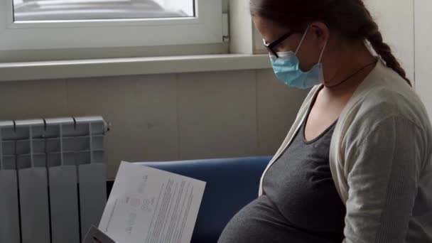 Ung Gravid Kvinna Medicin Skyddande Mask Läsa Soffan Väntar Utnämning — Stockvideo