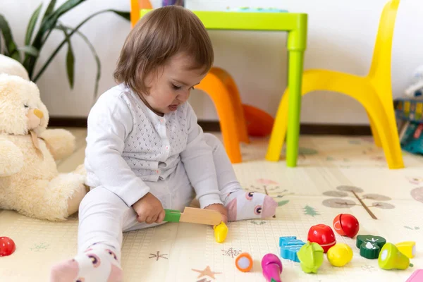 happy funny kid curly baby girl with educational toy blocks flowers. Children play at day care or preschool. Mess in kids room. Toddler build tower in kindergarten. Child playing with colorful toys.