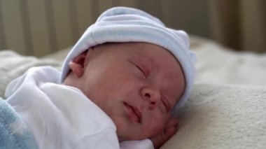Yakın plan Yeni Doğmuş Bebek Yüzü İlk Günler Mavi Göbek Arkaplanında Tatlı Uyuyan Bebek Portresi. Hayata Başlayan Çocuk Şapka 'da. Bebekler, Doğum, Doğumun İlk Anları, Başlangıç Konsepti.