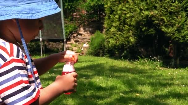 在闷热的夏天 可爱可爱的学龄前男孩在妈妈的身边吹泡泡肥皂泡 孩子们在院子里玩耍 室外晴天 公园或花园里的婴儿 家庭观念 — 图库视频影像