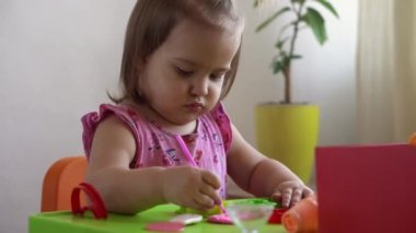 Çocuklar için heykel ve kil modelleme. 3-5 yaşlarındaki kız pembe hamur şekilli ve şekilli parmaklar ve plastik maket bıçağı kullanıyor. Oyun kilini kullanarak iyi motor becerileri ve çocuk yaratıcılığını geliştirmek.