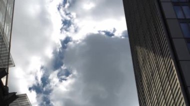 Londra 'daki gökdelenlerin iş merkezinin üzerinden geçen uçak. Öğleden sonra bulutlu, mavi gökyüzünde uçan bir uçakla yüksek binaların alt görüntüsü. Hava Taşımacılığı, Seyahat, Meslek kavramı