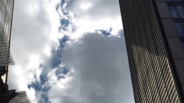 ロンドンの高層ビルのビジネスセンター上空の飛行機便 午後には雲が立ち並ぶ青い空の高層ビルの下からの眺め 航空輸送 位置情報の概念 — ストック動画