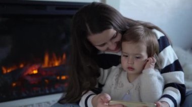 Neşeli, tapılası küçük kız, ebeveyn kontrollü akıllı telefon kullanarak öğrenmenin keyfini çıkarıyor. Mutlu aile, anne ve baba, anne ve baba, evde rahatlayan videolar izleyip, çizgi film uygulaması izliyorlar..