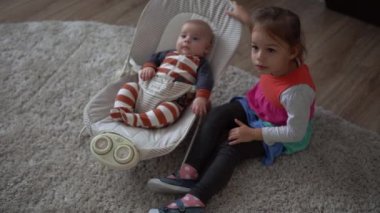 Çocukluk, annelik, aile, rahatlık. Çizgili pijamalı yeni doğmuş küçük bebek uyandı. Etrafa bakıp gülüyor. Kardeş kardeş gibi davranıyor..