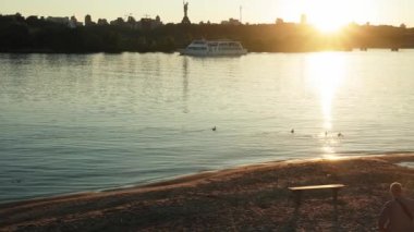 2021.06.25 - Kiev, Ukrayna: günbatımından önce geniş nehir Dinyeper manzarasının panoramik çekimi. Yat gemisi denizde ya da okyanusta kargo yelkeni açıyor. Su taşımacılığı, tatil, doğa, yaz konsepti.