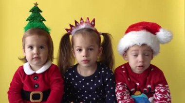 Duygusal Sevimli Mutlu Kardeşler Üç Arkadaş Bebek Kız ve Erkek Alkışlar Noel Baba Takım Elbiseli Adam Sarı Arkaplan 'daki kameraya bakıyor. Doğum gününü kutlayan çocuk Noel Sahnesi oynuyor. Çocuk Yılbaşını Eğlenerek Geçiriyor.