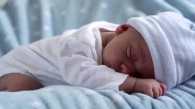Yakın plan Yeni Doğmuş Bebek Yüzü İlk Günler Mavi Yıldızlı Arkaplanda Tatlı Uyuyor. Hayata Başlayan Çocuk Şapka 'da. Bebekler, Doğum, Doğumun İlk Anları, Başlangıç Konsepti.
