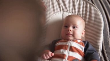 Omuz omuza. Çocukluk, annelik, aile. Çizgili pijamalı yeni doğmuş bebek uyanmış etrafa bakıyor gülümseyen oyunlar oynuyor annemi evde tanıdı..