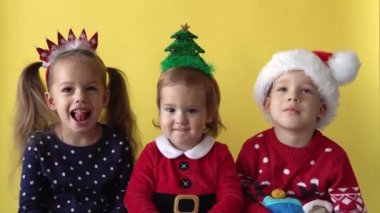 Duygusal Sevimli 3 kardeş, arkadaşlar, bebek kız ve Noel Baba kostümü içinde öpüşen çocuk sarı arka planda kameraya bakıyor. Doğum gününü kutlayan çocuk Noel Sahnesi oynuyor. Çocuk Yılbaşını Eğlenerek Geçiriyor.