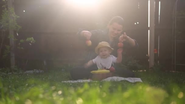 Šťastná Mladá Veselá Matka Drží Dítě Jíst Ovoce Zelené Trávě — Stock video