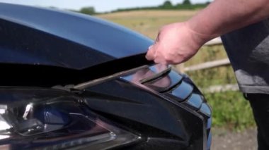 Hüsrana uğramış adam kaza arabasını tamir ediyor. Bozuk Arabadaki Üzücü Erkek. Araç Kontrol Motoru Hasar Sorunları. Şoför Acil Servis 'i arıyor. Otomobil kazası. Hood Otomobil Aç.
