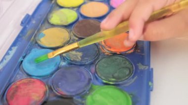 Close up Talented little girl Female Artist Draws Mother Sun Summer Flover drawing at Home. Colorful, Emotional Happy painting with Brush water colors. Contemporary Painter Creating Abstract Modern