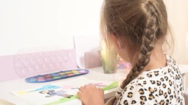 Talented Creative Child Girl Female Artist Draws with Her Hands on Paper, Using Fingers Paints Brush Creates Colorful, Kid Drawing on table at Home. Painter Creating Abstract Modern Art. Childhood.
