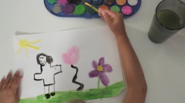 Talented Creative Child Girl Female Artist Draws with Her Hands on Paper, Using Fingers Paints Brush Creates Colorful, Kid Drawing on table at Home. Painter Creating Abstract Modern Art. Childhood.