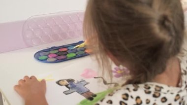 Talented Creative Child Girl Female Artist Draws with Her Hands on Paper, Using Fingers Paints Brush Creates Colorful, Kid Drawing on table at Home. Painter Creating Abstract Modern Art. Childhood.