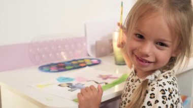 Talented Creative Child Girl Female Artist Draws with Her Hands on Paper, Using Fingers Paints Brush Creates Colorful, Kid Drawing on table at Home. Painter Creating Abstract Modern Art. Childhood.
