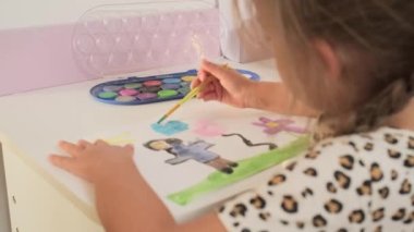 Talented Creative Child Girl Female Artist Draws with Her Hands on Paper, Using Fingers Paints Brush Creates Colorful, Kid Drawing on table at Home. Painter Creating Abstract Modern Art. Childhood.