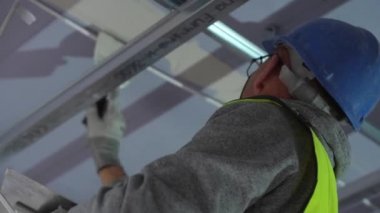 Hard male work on construction site. professional worker in special uniforms Contractors Safety Hats repairing ceiling wall inside building. Builders equipment at workplace. industrial premises.