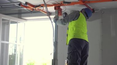 Hard male work on construction site. Two professional workers in special uniforms Contractors Safety Hats repairing ceiling wall inside building. Builders equipment at workplace. industrial premises.