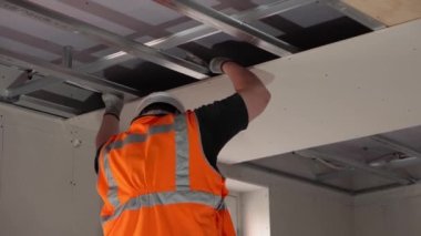 Hard male work on construction site. Two professional workers in special uniforms Contractors Safety Hats repairing ceiling wall inside building. Builders equipment at workplace. industrial premises.