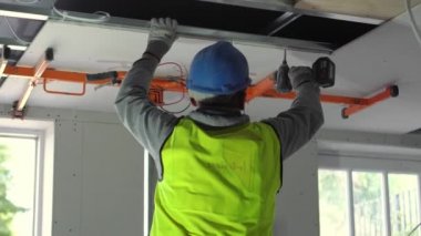 Hard male work on construction site. Two professional workers in special uniforms Contractors Safety Hats repairing ceiling wall inside building. Builders equipment at workplace. industrial premises.