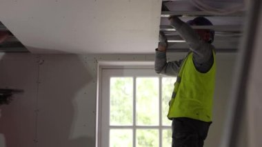 Hard male work on construction site. Two professional workers in special uniforms Contractors Safety Hats repairing ceiling wall inside building. Builders equipment at workplace. industrial premises.