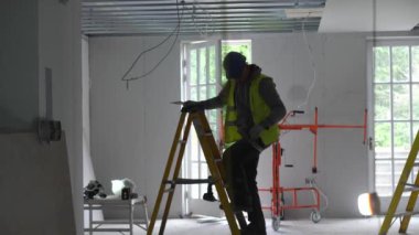 Hard male work on construction site. Two professional workers in special uniforms Contractors Safety Hats repairing ceiling wall inside building. Builders equipment at workplace. industrial premises.