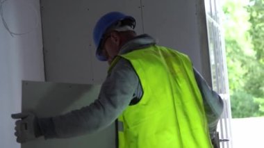 Hard male work on construction site. professional worker in special uniforms Contractors Safety Hats repairing ceiling wall inside building. Builders equipment at workplace. industrial premises.