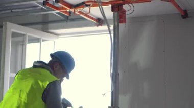 Hard male work on construction site. Two professional workers in special uniforms Contractors Safety Hats repairing ceiling wall inside building. Builders equipment at workplace. industrial premises.
