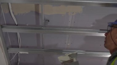 Hard male work on construction site. professional worker in special uniforms Contractors Safety Hats repairing ceiling wall inside building. Builders equipment at workplace. industrial premises.