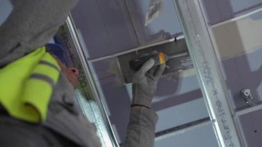 Hard male work on construction site. professional worker in special uniforms Contractors Safety Hats repairing ceiling wall inside building. Builders equipment at workplace. industrial premises.