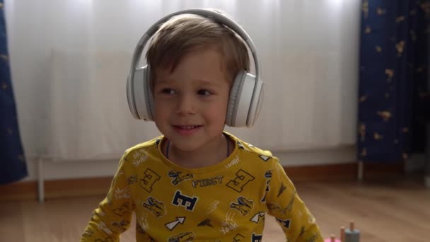 Close Handsome Smiling Boy Listening Music Headphones Indoor Children Technology — Stockvideo