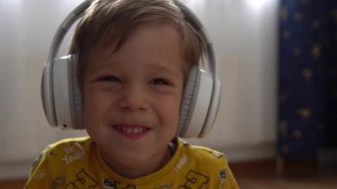 Kapalı mekanda müzik kulaklığı dinleyen yakışıklı çocuk. Çocuklar ve teknoloji. Müzik aşkı, çocuklar hayaller, hobiler. Yetenekli, mutlu, küçük çocuk kiralama. Çocukluk, müzik, hobi.