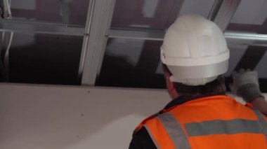 Hard male work on construction site. Two professional workers in special uniforms Contractors Safety Hats repairing ceiling wall inside building. Builders equipment at workplace. industrial premises.