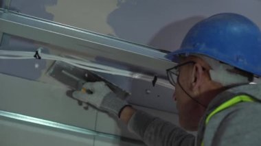 Hard male work on construction site. professional worker in special uniforms Contractors Safety Hats repairing ceiling wall inside building. Builders equipment at workplace. industrial premises.