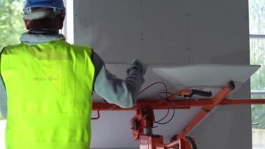 Hard male work on construction site. Two professional workers in special uniforms Contractors Safety Hats repairing ceiling wall inside building. Builders equipment at workplace. industrial premises.