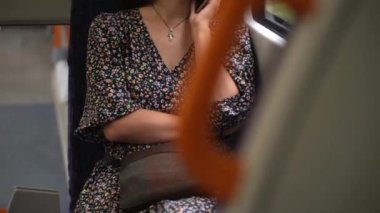 Close shot of young attractive Ukraine female in glasses sitting on moving city metro train. Woman calling typing text message on mobile phone. Pretty Lady waving hands say goodbye. Traveling alone.